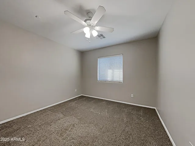 an empty room with a chandelier fan and windows