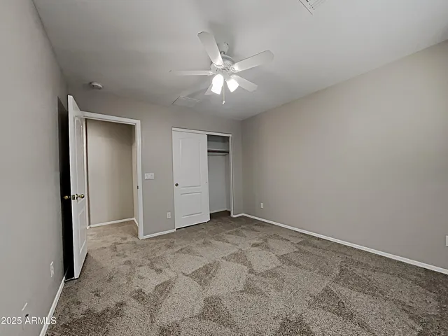 an empty room with closet and a ceiling fan