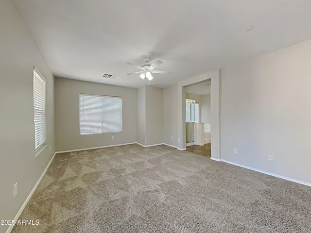 an empty room with windows and chandelier fan