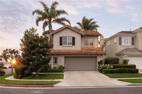 a front view of a house with a garden and palm trees