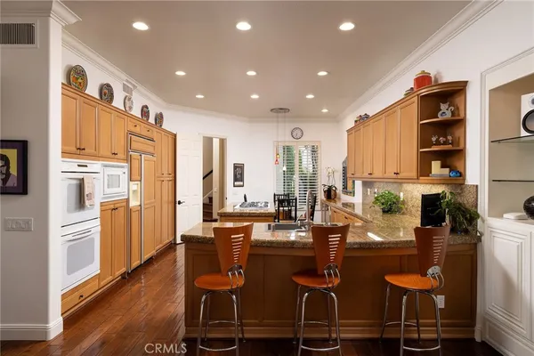 a kitchen with stainless steel appliances a refrigerator a stove a sink dishwasher and white cabinets with wooden floor