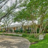 a view of house in front of a big yard with large trees