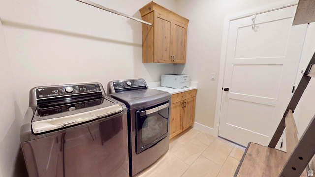 1127 4240 North Enoch, UT 84721 - Photo 27 of 56 Laundry area with washing machine and clothes dryer, light tile patterned floors, and cabinet space