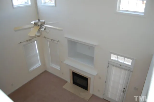 a view of a livingroom with a fireplace a ceiling fan and windows