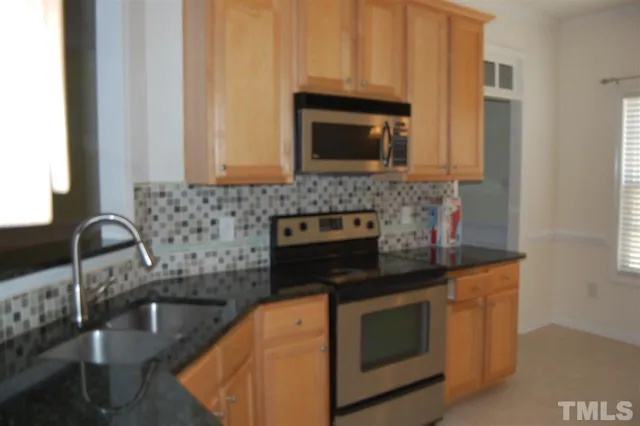 a kitchen with granite countertop white cabinets stainless steel appliances and a sink