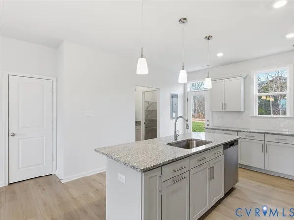 a kitchen with a sink dishwasher and white cabinets with wooden floor