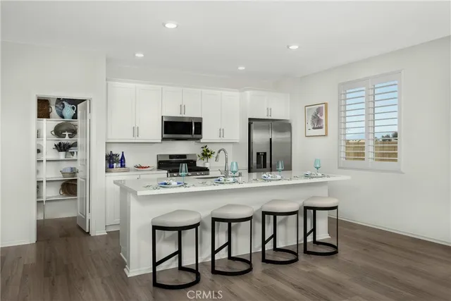 a kitchen with stainless steel appliances a dining table chairs microwave and sink