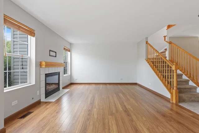 a view of an empty room with wooden floor fireplace and a window