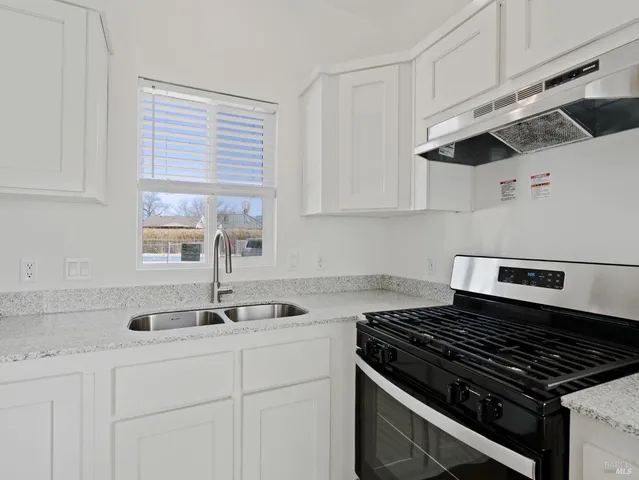 a kitchen with granite countertop a sink stove and cabinets