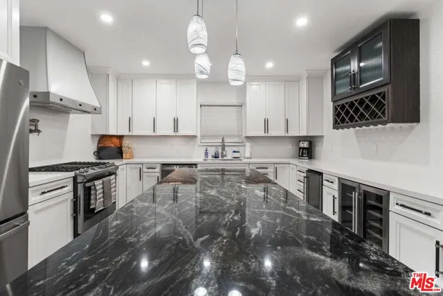 a large kitchen with stainless steel appliances granite countertop a stove a sink a refrigerator and a microwave