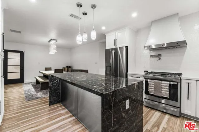 a kitchen with stainless steel appliances granite countertop a stove refrigerator and cabinets