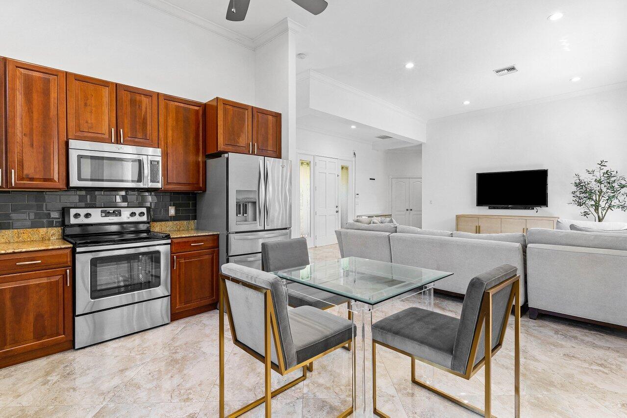 4023 Northwest 58th Street Boca Raton, FL 33496 - Photo 4 of 20 a kitchen with stainless steel appliances a stove a sink island and a refrigerator
