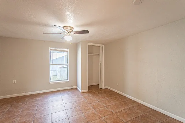 an empty room with windows and fan