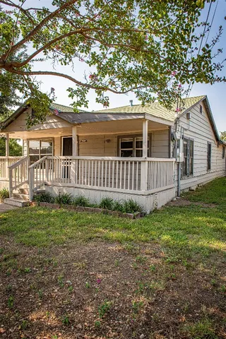 a view of a house with a yard and a large tree