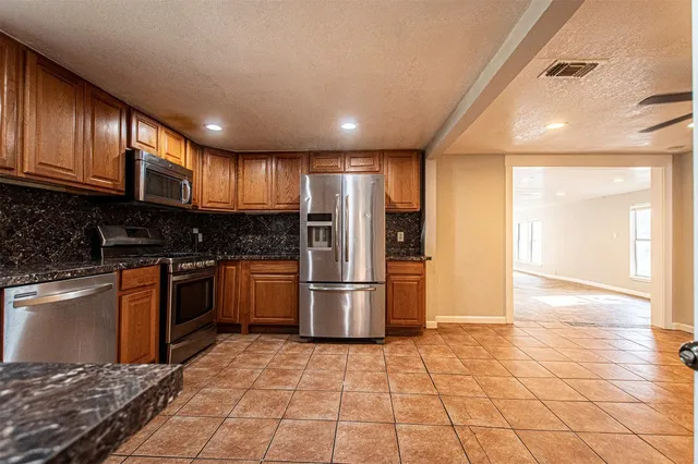 a kitchen with stainless steel appliances granite countertop a stove a sink and a microwave