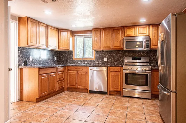 a view of a kitchen with kitchen island granite countertop a refrigerator and a sink