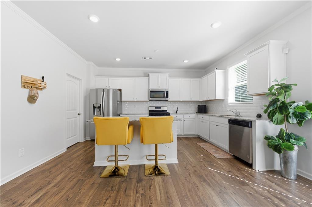7565 Jennadee Drive Fairburn, GA 30213 - Photo 8 of 42 a living room with kitchen island granite countertop furniture wooden floor and a potted plant