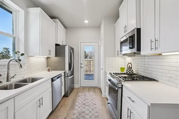 a kitchen with stainless steel appliances a sink stove refrigerator and cabinets