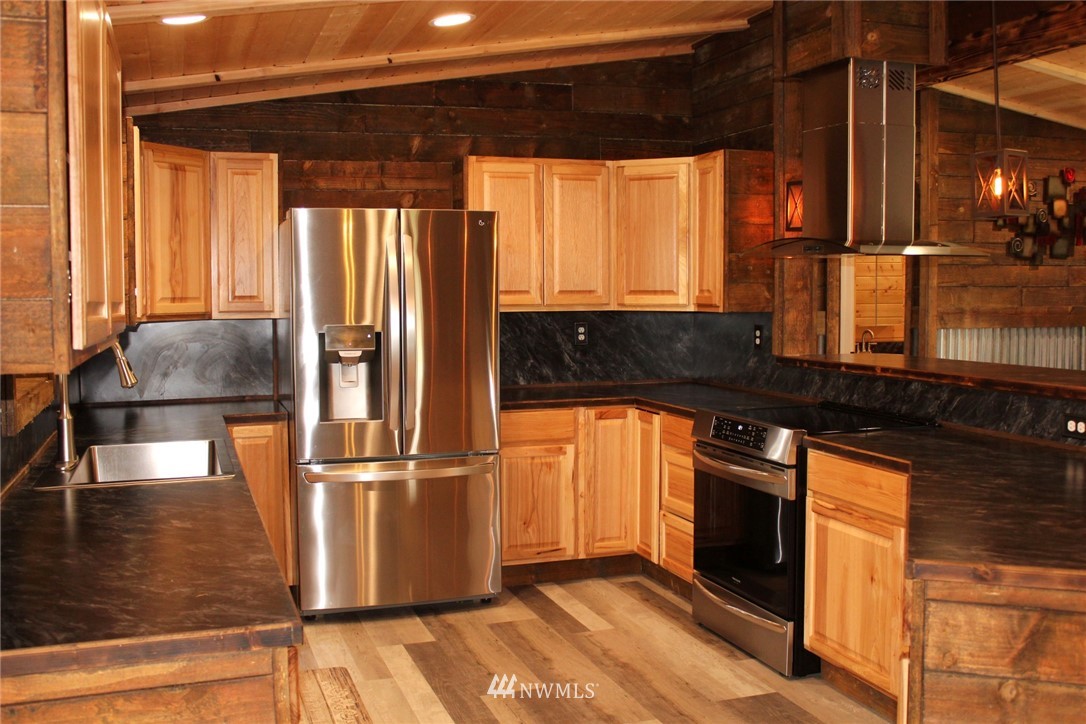 18337 Forstrom Street Southwest Rochester, WA 98579 - Photo 2 of 26 a kitchen with granite countertop a refrigerator and a stove top oven