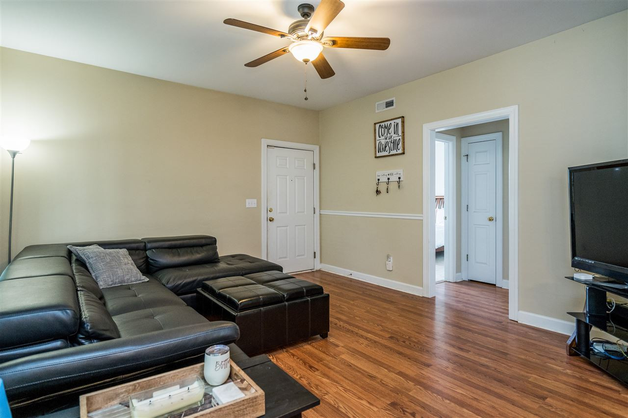 Enjoy this spacious living room with gorgeous hardwoods, ceiling fan, and neutral paint! Living Room