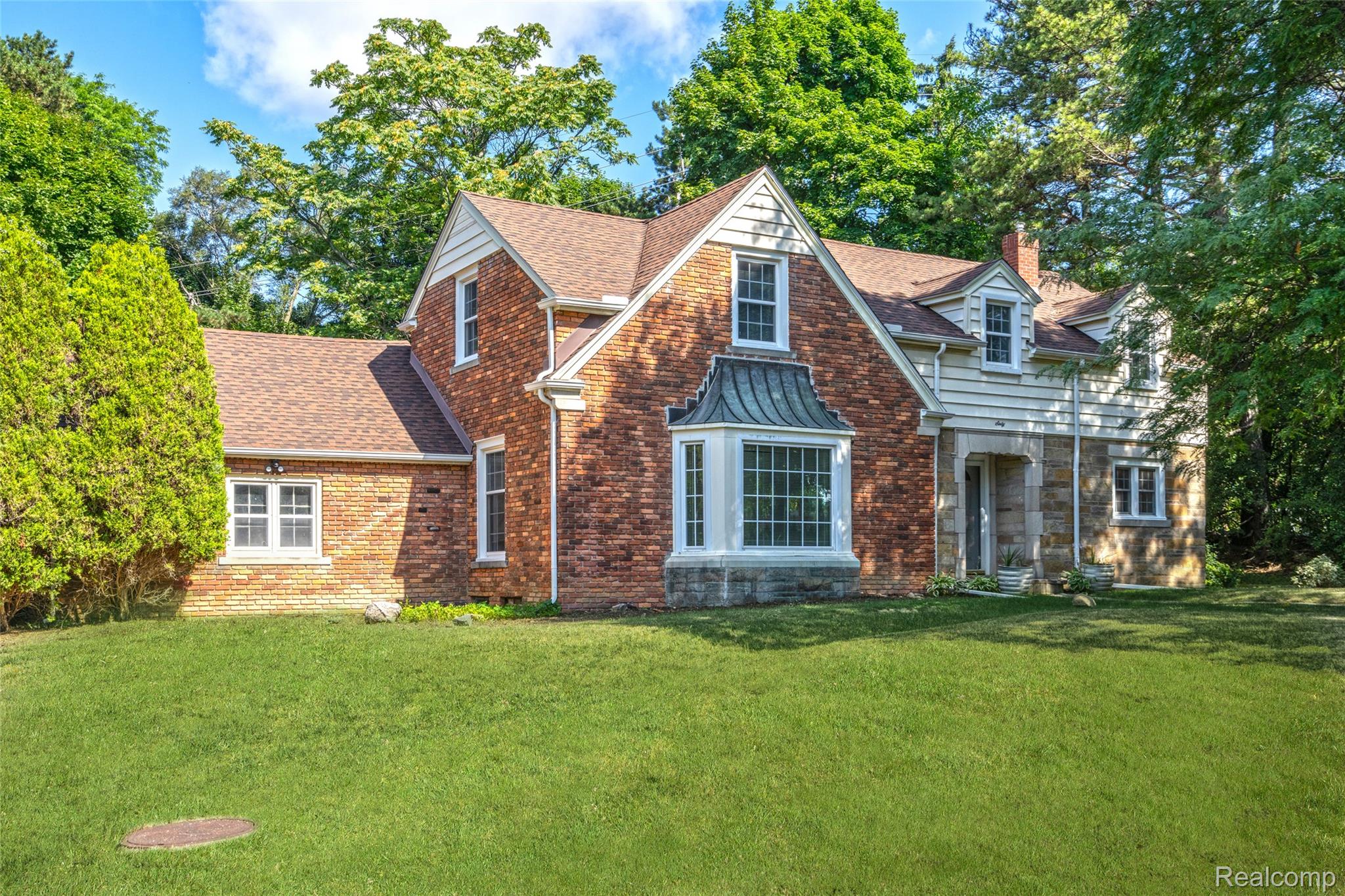 60 Devon Road Bloomfield Hills, MI 48302 - Photo 2 of 50 Brick and stone exterior with a prominent bay window featuring a copper-tone awning