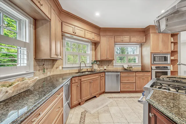a kitchen with kitchen island granite countertop wooden cabinets and a large window