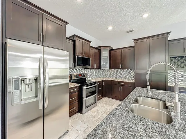 a modern kitchen with stainless steel appliances granite countertop a refrigerator and a sink