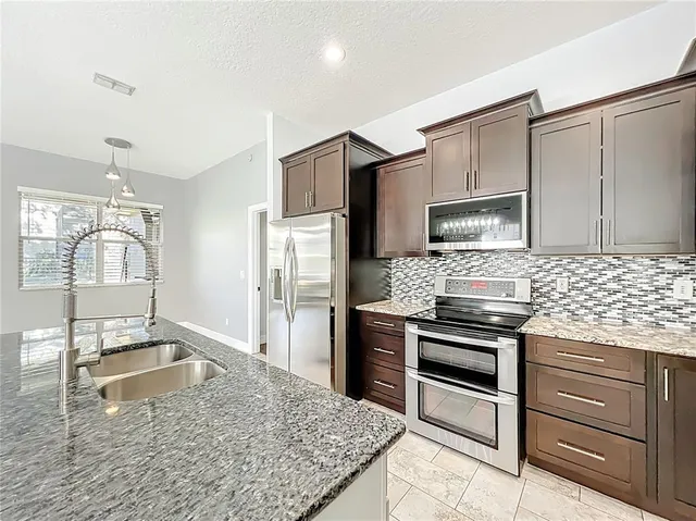 a kitchen with granite countertop a stove cabinets and stainless steel appliances