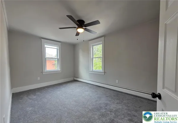 an empty room with windows and fan