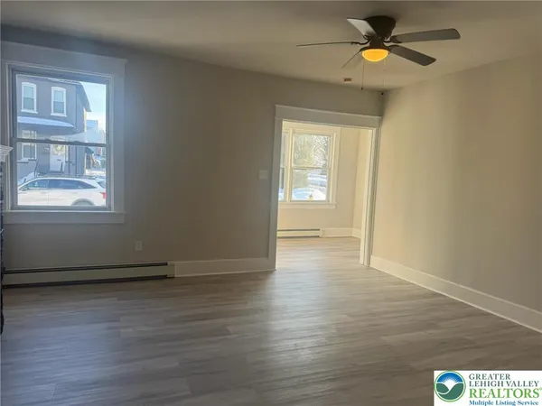 an empty room with wooden floor and windows