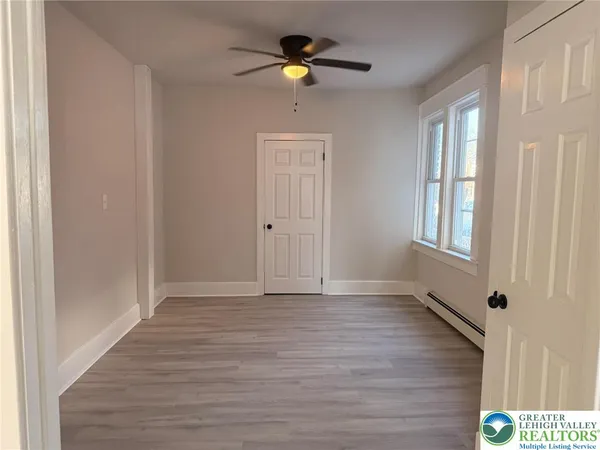 a view of an empty room with a window and wooden floor