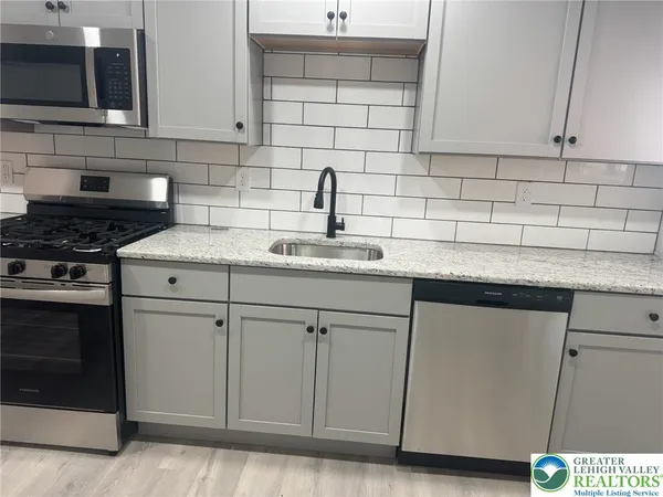 a kitchen with stainless steel appliances granite countertop a sink stove and cabinets
