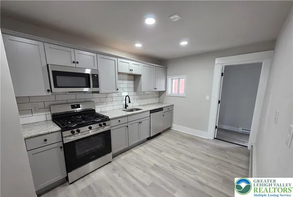 a kitchen with granite countertop a stove top oven a sink dishwasher and a refrigerator with wooden floor