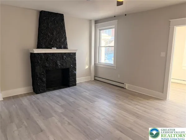 an empty room with wooden floor fireplace and windows