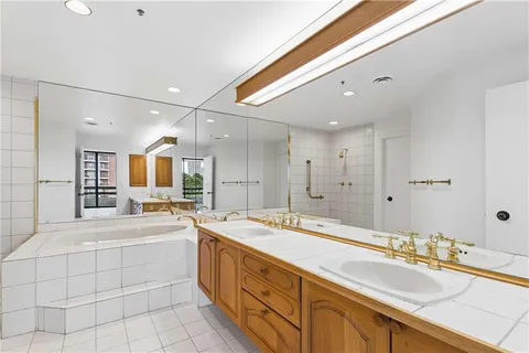 a large white bathroom with a granite countertop sink mirror and bathtub