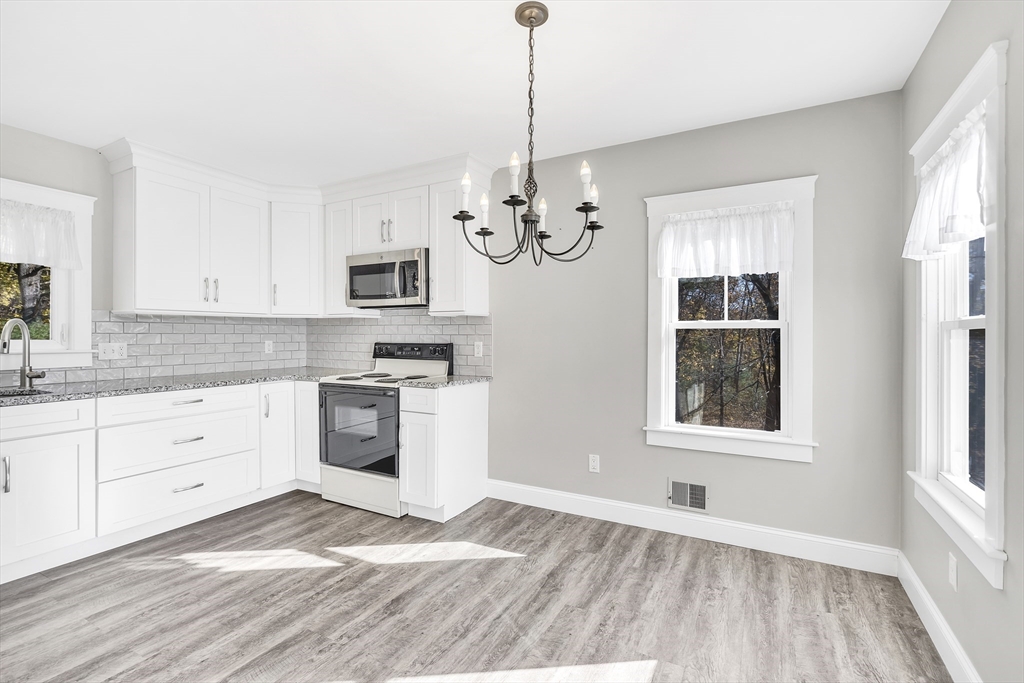 16 County Street Foxboro, MA 02035 - Photo 7 of 33 a kitchen with granite countertop a stove a sink and a chandelier