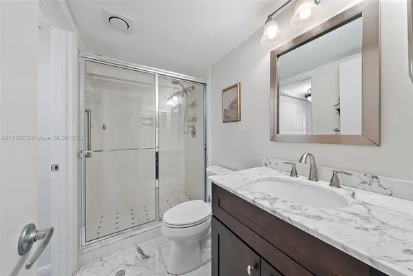 a bathroom with a granite countertop sink a toilet and shower
