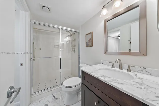 a bathroom with a granite countertop sink a toilet and shower