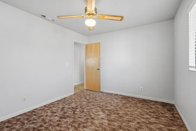 an empty room with closet and a ceiling fan