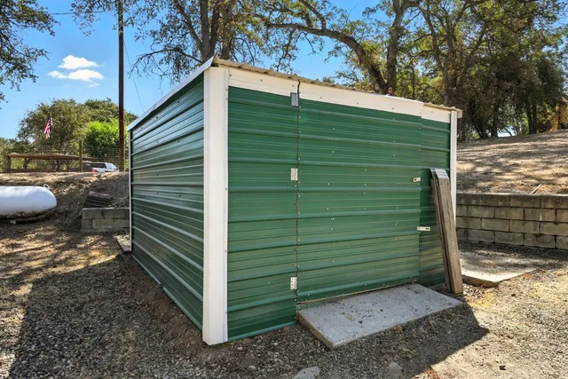 a view of a wooden house with a large window and lawn chairs