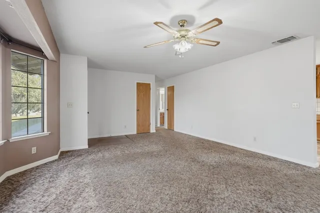 an empty room with windows and fan