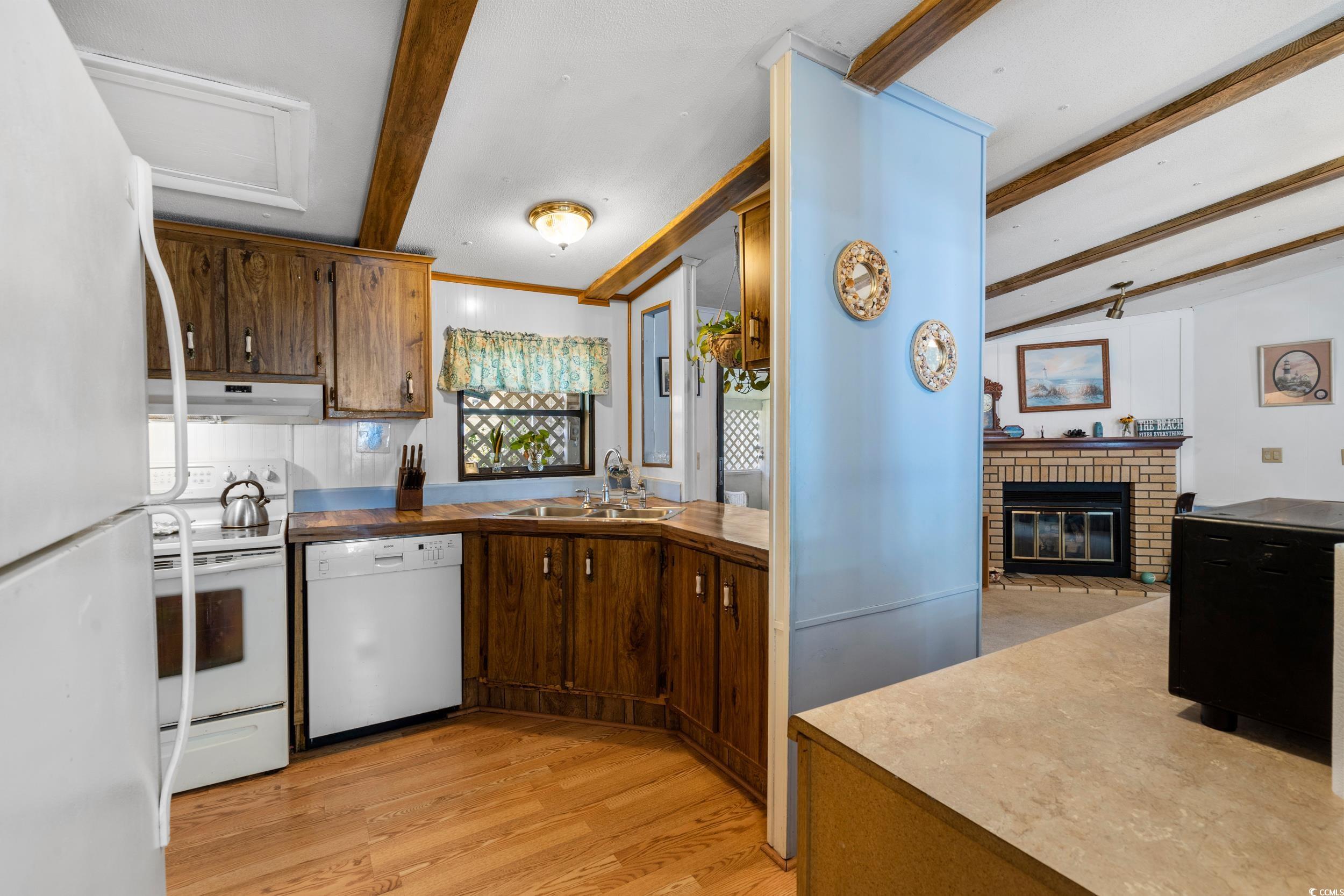 17 Crooked Island Circle Murrells Inlet, SC 29576 - Photo 11 of 39 Kitchen with white appliances, a sink, beam ceiling, under cabinet range hood, and light wood-style floors