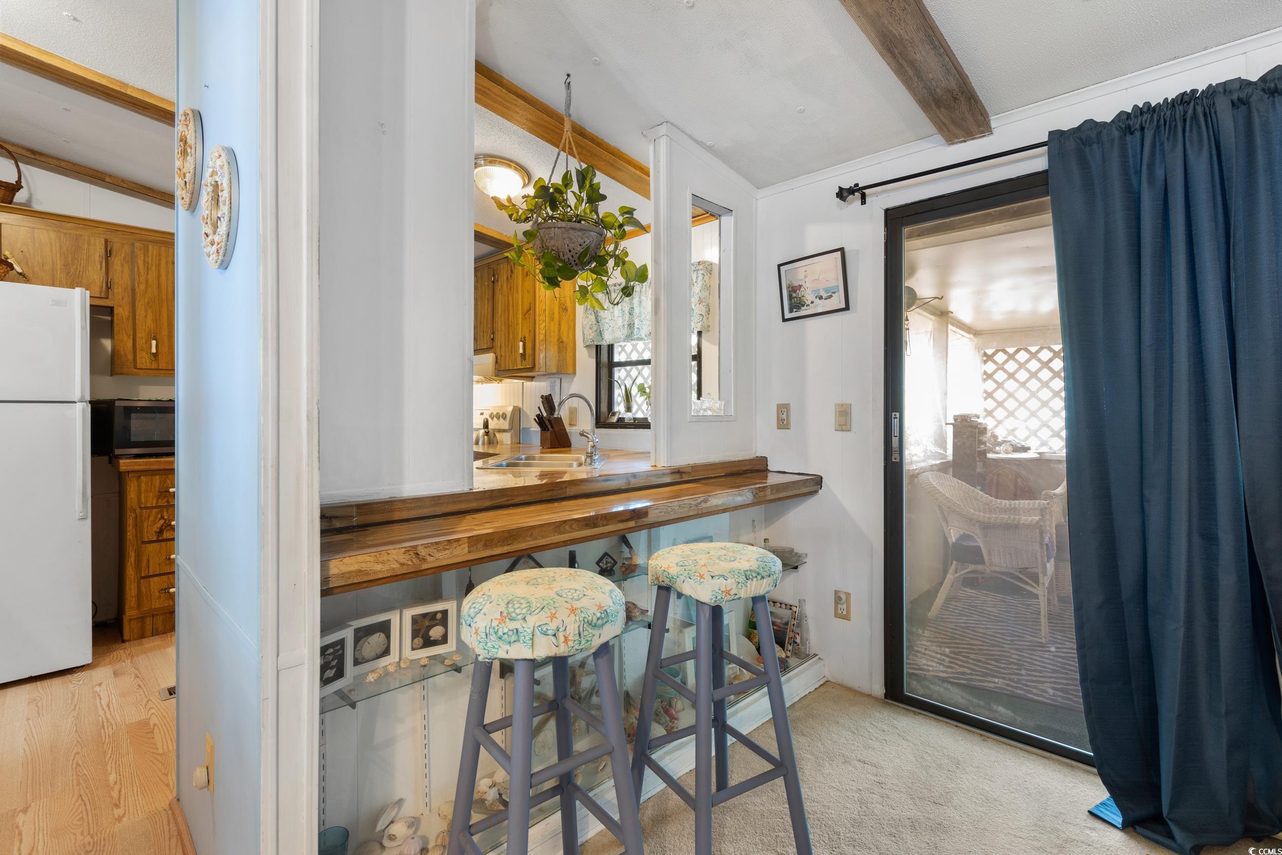 17 Crooked Island Circle Murrells Inlet, SC 29576 - Photo 13 of 39 Kitchen with freestanding refrigerator, stainless steel microwave, beamed ceiling, a sink, and brown cabinets