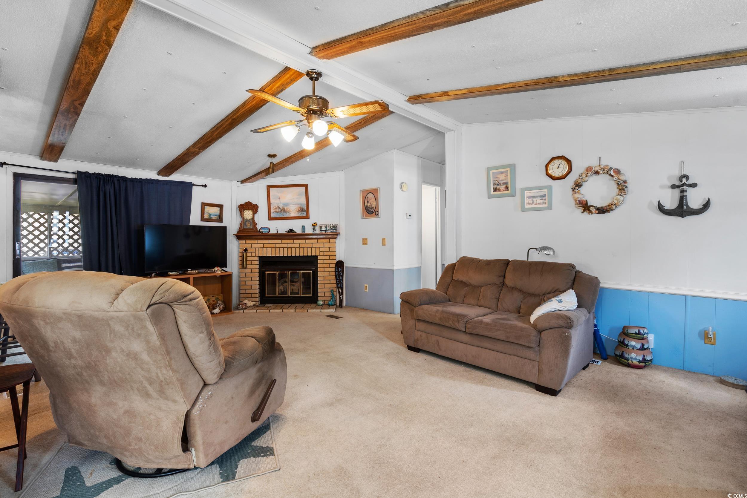 17 Crooked Island Circle Murrells Inlet, SC 29576 - Photo 4 of 39 Living room featuring carpet, wainscoting, a ceiling fan, and a brick fireplace