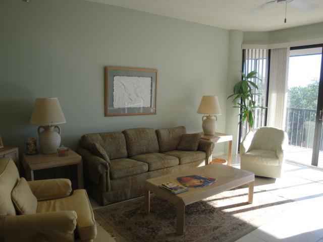 221 Northeast Plantation Road, Unit 415 Jensen Beach, FL 34957 - Photo 2 of 6 a living room with furniture a lamp wooden floor and a large window