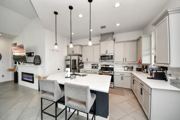 a kitchen with stainless steel appliances a stove a sink a oven a kitchen island a stove a table and chairs