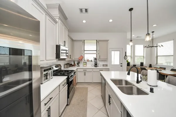 a large white kitchen with lots of counter space a sink and appliances
