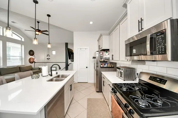 a kitchen with stainless steel appliances a stove a sink a microwave a refrigerator a stove and cabinets