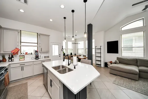 a kitchen with a sink a counter top space and living room view