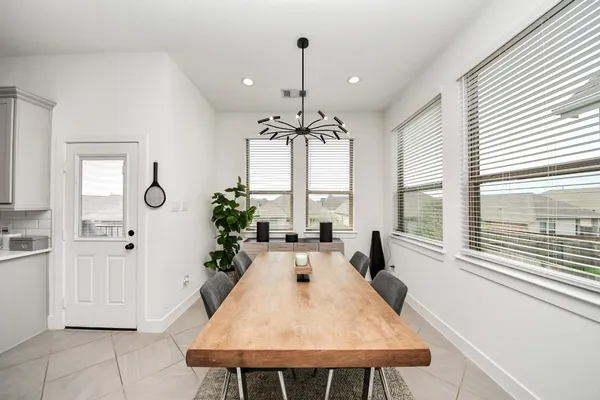 a dining room with chandelier and wooden floor